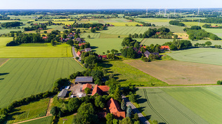 kleines Dorf mit Windrädern in ländlicher Gegend (verweist auf: Bayern: Staatliche Leistungen tragen zur Reduzierung regionaler Einkommensungleichheiten bei) | Quelle: © Christian Schwier / Adobe Stock